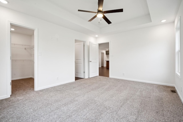 unfurnished bedroom with carpet, a raised ceiling, and baseboards