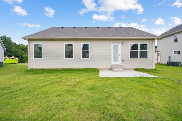 rear view of property featuring entry steps, roof with shingles, a lawn, and a patio