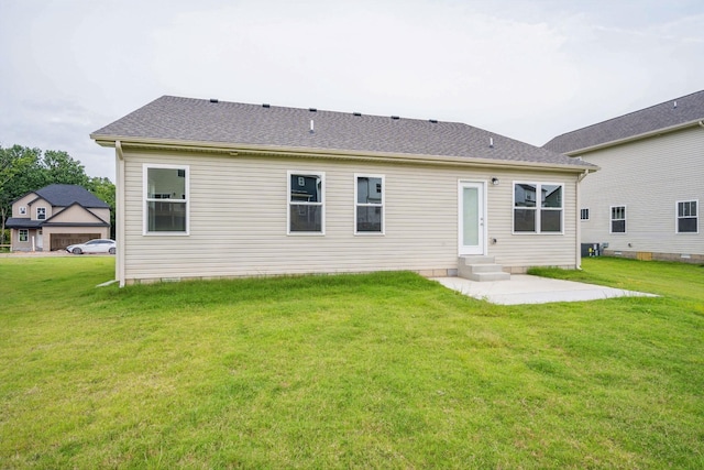 back of house with entry steps, a patio area, a shingled roof, and a lawn