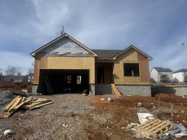 unfinished property featuring an attached garage and gravel driveway