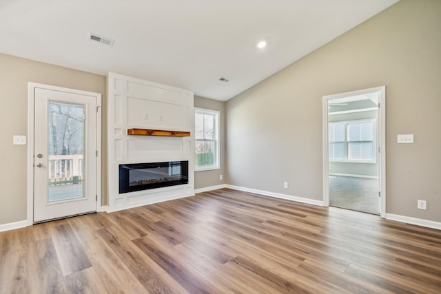 unfurnished living room featuring lofted ceiling and light wood-type flooring