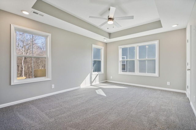 carpeted spare room featuring a raised ceiling and ceiling fan