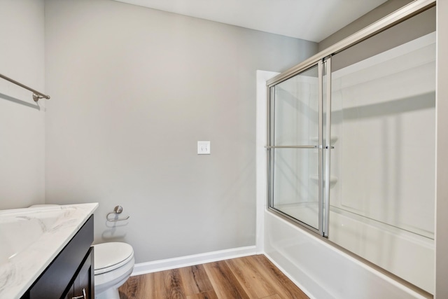 full bathroom featuring vanity, hardwood / wood-style floors, shower / bath combination with glass door, and toilet