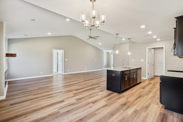 kitchen featuring sink, decorative light fixtures, a center island with sink, light stone countertops, and ceiling fan with notable chandelier