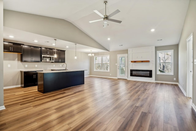 kitchen with hanging light fixtures, plenty of natural light, a center island with sink, and light hardwood / wood-style floors