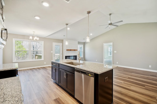 kitchen featuring sink, light stone counters, hanging light fixtures, light hardwood / wood-style flooring, and dishwasher