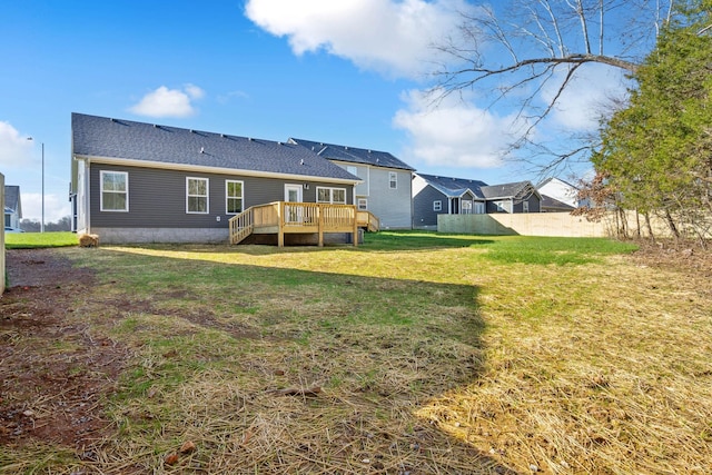 rear view of property with a wooden deck and a lawn