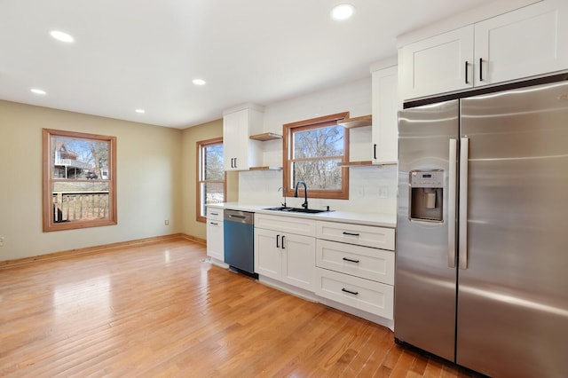 kitchen featuring stainless steel appliances, sink, light wood-type flooring, and white cabinets