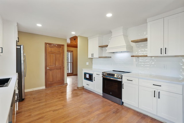 kitchen featuring white cabinetry, decorative backsplash, stainless steel appliances, and custom range hood