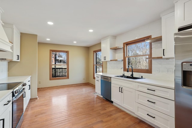 kitchen featuring sink, tasteful backsplash, light wood-type flooring, appliances with stainless steel finishes, and white cabinets