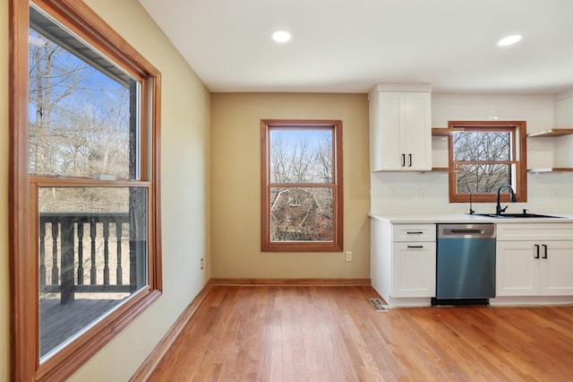 kitchen with sink, white cabinetry, tasteful backsplash, light wood-type flooring, and stainless steel dishwasher