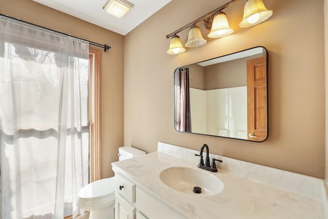 bathroom with walk in shower, vanity, and toilet