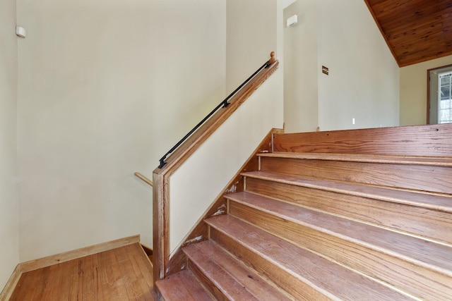 stairway featuring lofted ceiling, wood-type flooring, and wooden ceiling