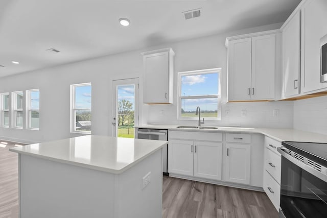 kitchen featuring sink, range with electric stovetop, white cabinets, and a kitchen island