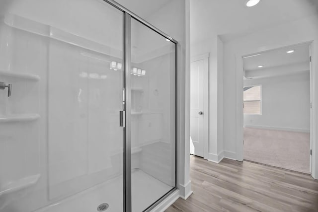 bathroom with hardwood / wood-style flooring and a shower with shower door