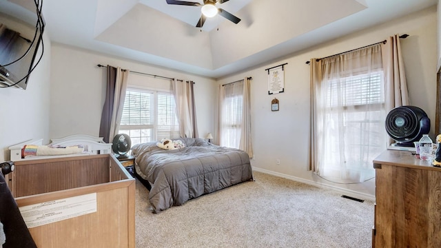 bedroom with ceiling fan, a raised ceiling, and light carpet