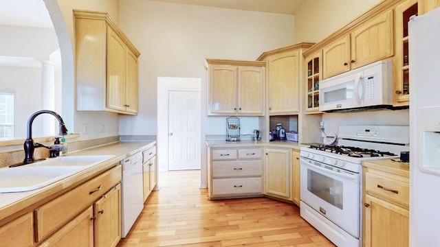 kitchen with light brown cabinetry, sink, and white appliances