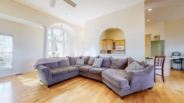 living room with a towering ceiling, light hardwood / wood-style floors, and a healthy amount of sunlight