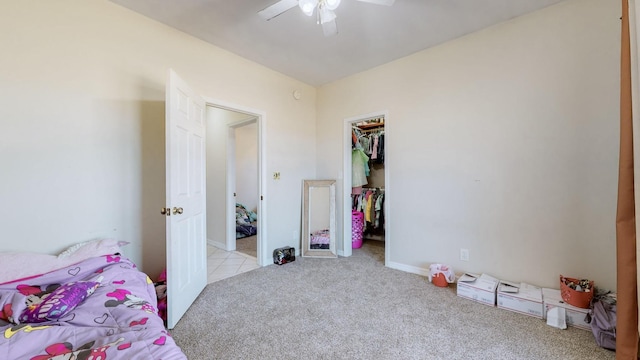 carpeted bedroom with a spacious closet, ceiling fan, and a closet