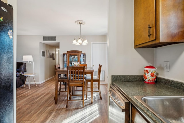 dining space featuring sink, a chandelier, and light hardwood / wood-style flooring