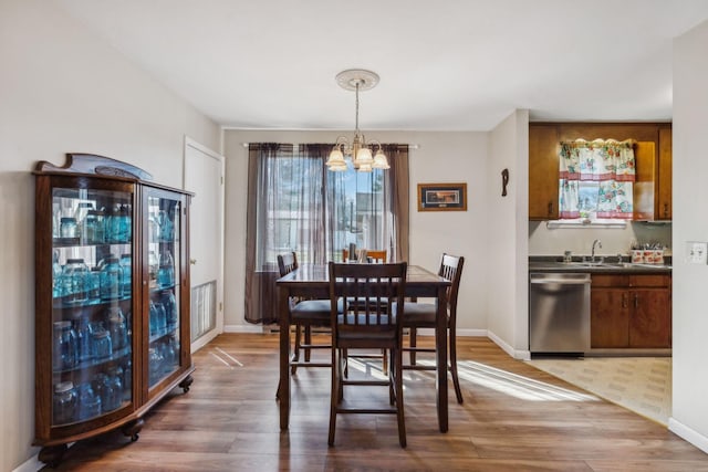 dining area with wood-type flooring, sink, and a notable chandelier