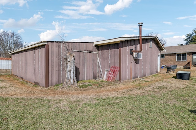 view of outbuilding featuring cooling unit and a lawn