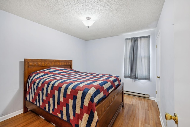 bedroom featuring baseboard heating, a textured ceiling, and light wood-type flooring