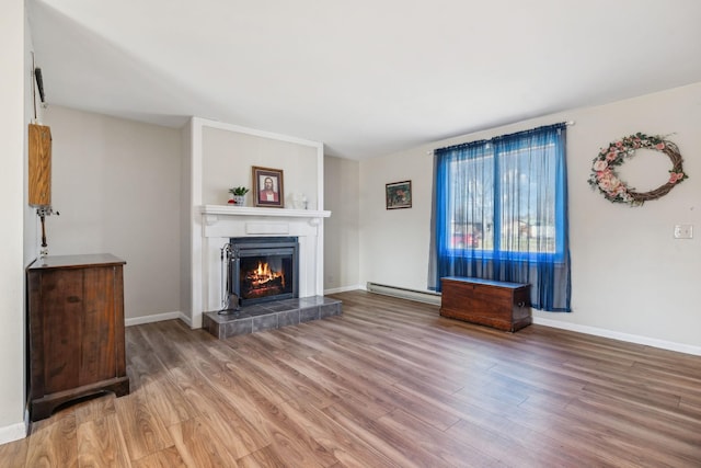 unfurnished living room with a tiled fireplace, hardwood / wood-style floors, and a baseboard heating unit