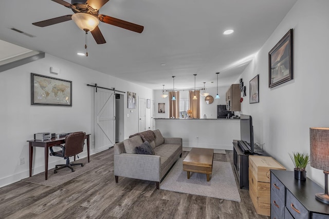 living room with dark hardwood / wood-style floors, ceiling fan, and a barn door