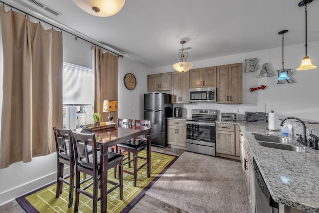 kitchen with sink, light stone counters, tasteful backsplash, decorative light fixtures, and stainless steel appliances