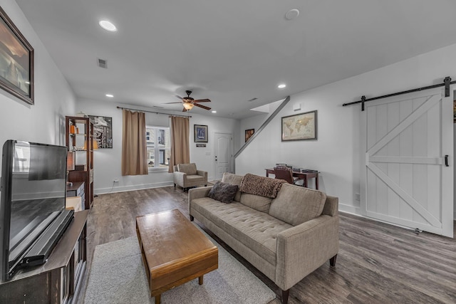 living room featuring a barn door, hardwood / wood-style floors, and ceiling fan