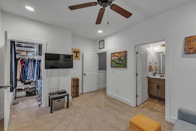 bedroom with ensuite bath, light colored carpet, a closet, and ceiling fan