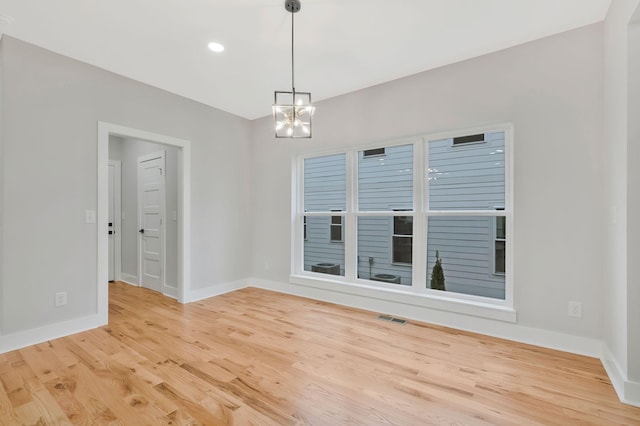 empty room with a notable chandelier and light wood-type flooring