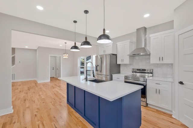 kitchen featuring white cabinetry, hanging light fixtures, a kitchen island with sink, stainless steel appliances, and wall chimney exhaust hood