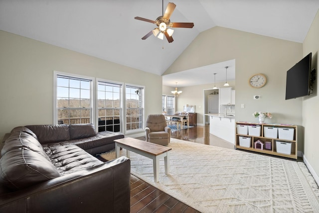 living room with ceiling fan with notable chandelier, dark wood-type flooring, and high vaulted ceiling