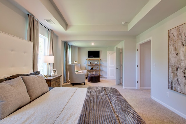 bedroom featuring light colored carpet and a tray ceiling