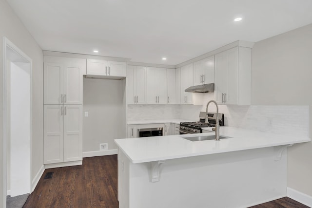 kitchen featuring stainless steel gas stove, sink, kitchen peninsula, and white cabinets