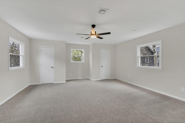 carpeted spare room with ceiling fan and plenty of natural light