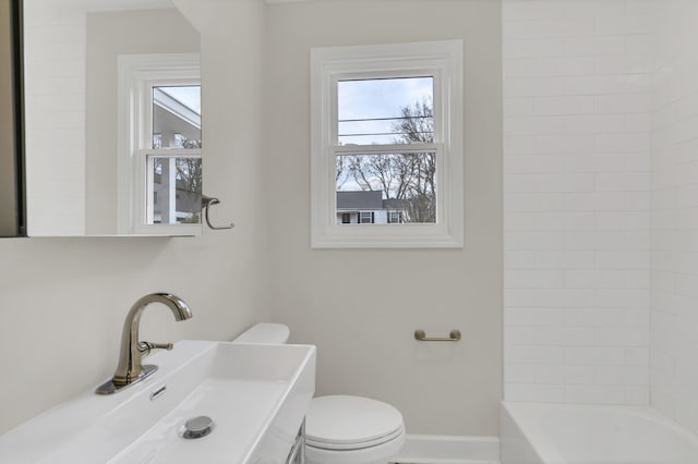 bathroom with sink, a bathtub, and toilet