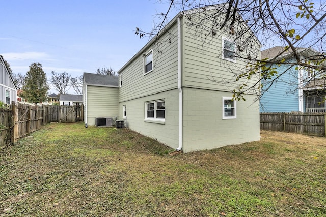 rear view of property featuring a yard and central AC unit