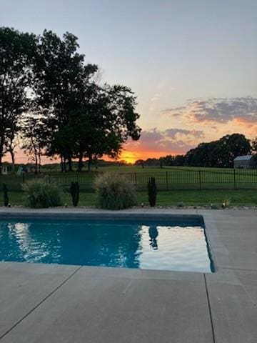 pool at dusk with a lawn and a patio