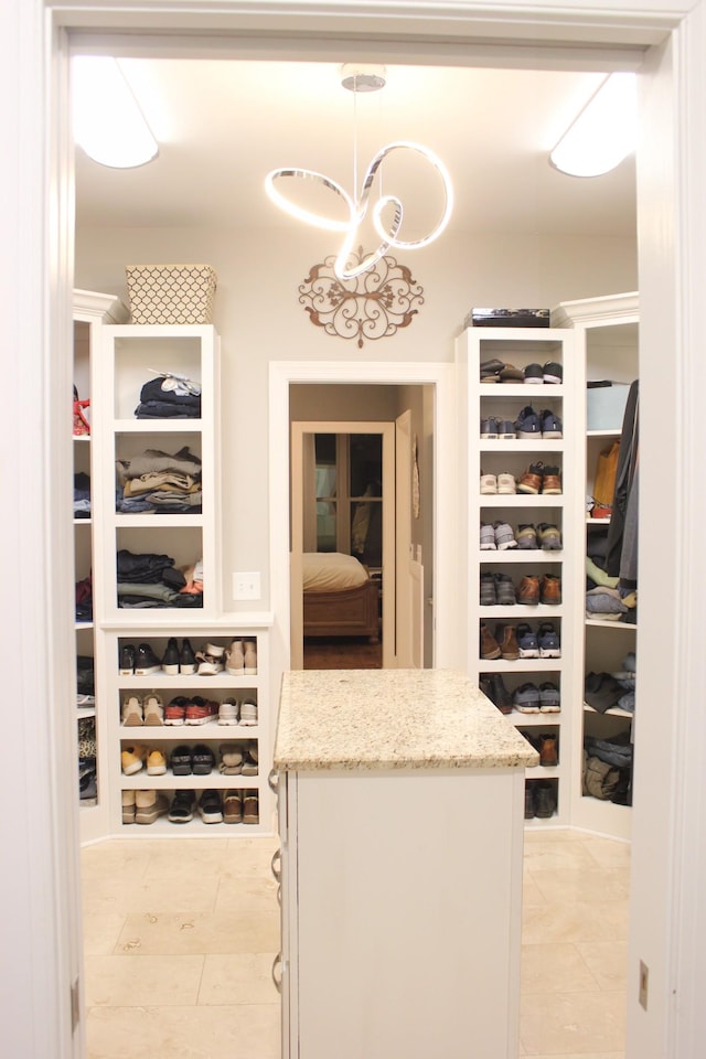 walk in closet with light tile patterned flooring and a chandelier