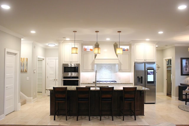 kitchen featuring light stone counters, appliances with stainless steel finishes, an island with sink, and custom range hood