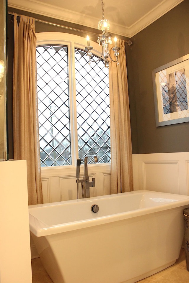 bathroom with a notable chandelier, crown molding, and a tub