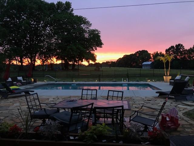 pool at dusk featuring a patio area