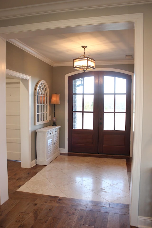 doorway to outside featuring a notable chandelier, crown molding, light hardwood / wood-style flooring, and french doors