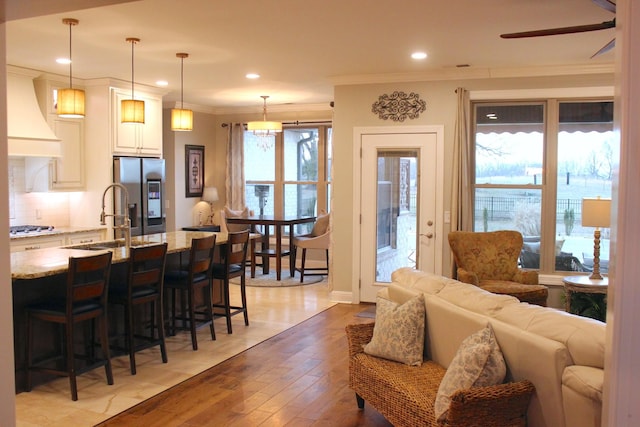 living room with ornamental molding, sink, ceiling fan, and light hardwood / wood-style floors