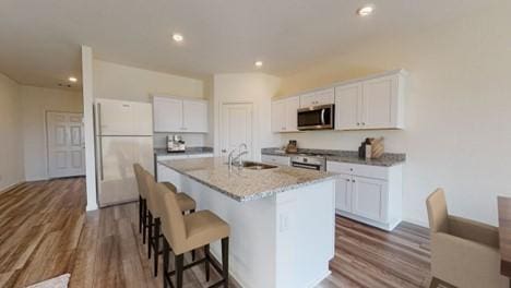 kitchen with a kitchen island with sink, sink, stainless steel appliances, and white cabinets