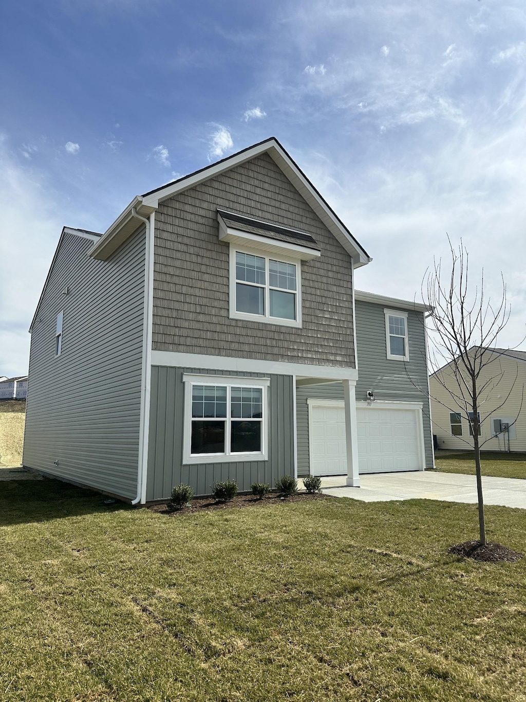 view of front of home featuring concrete driveway, a front lawn, board and batten siding, and an attached garage