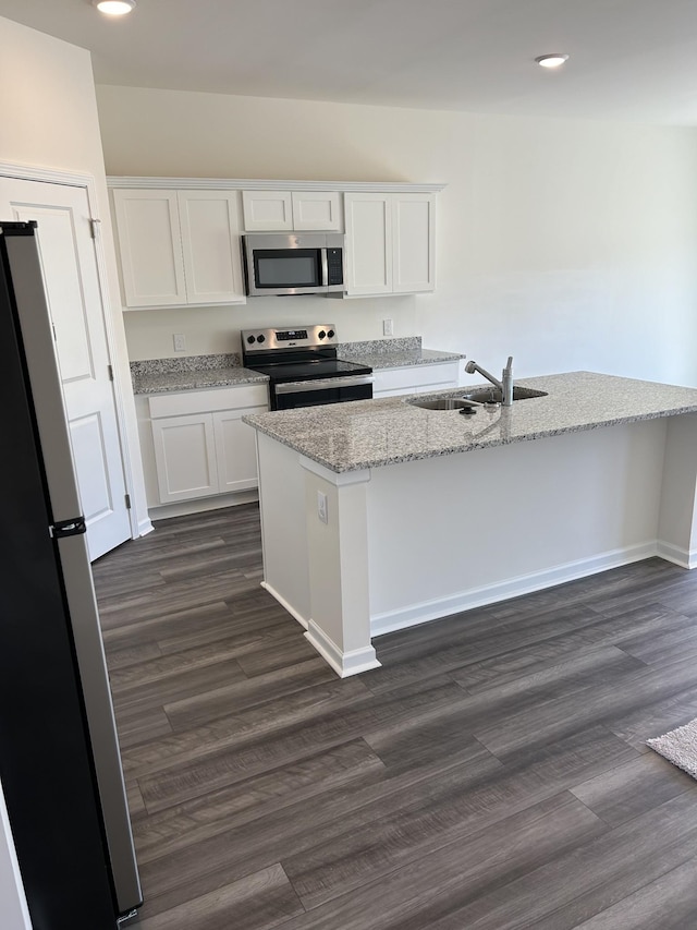kitchen with dark wood-style flooring, stainless steel appliances, white cabinetry, a sink, and light stone counters